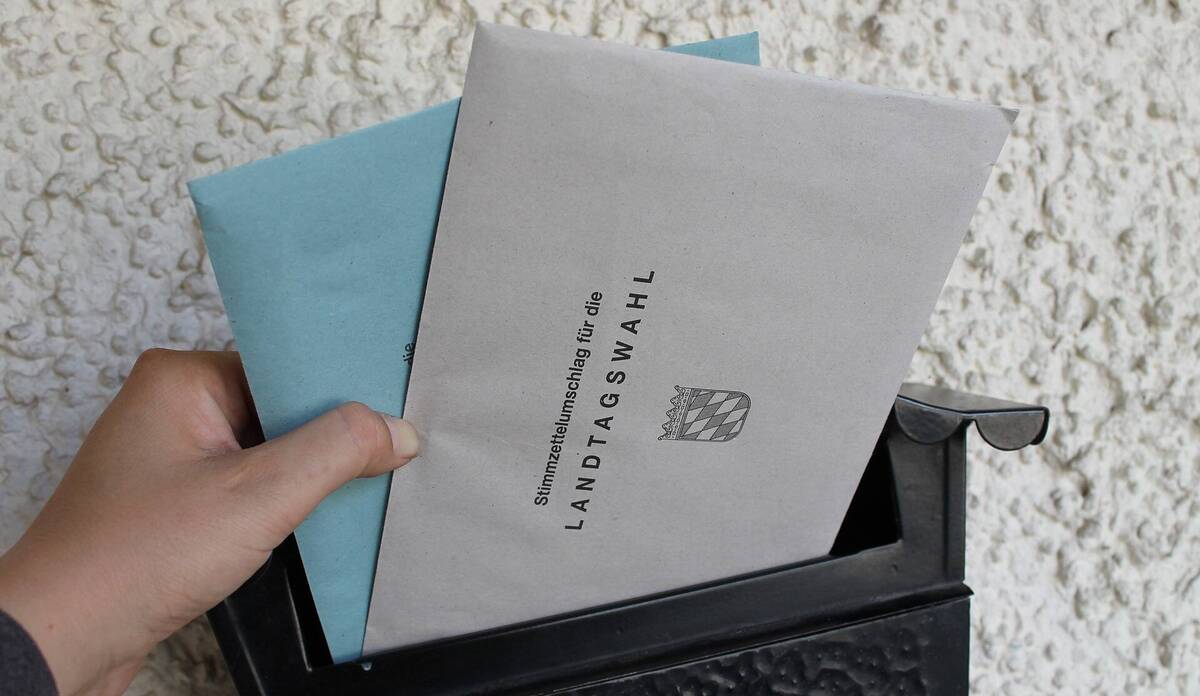 Briefwahlumschlag in den Briefkasten stecken